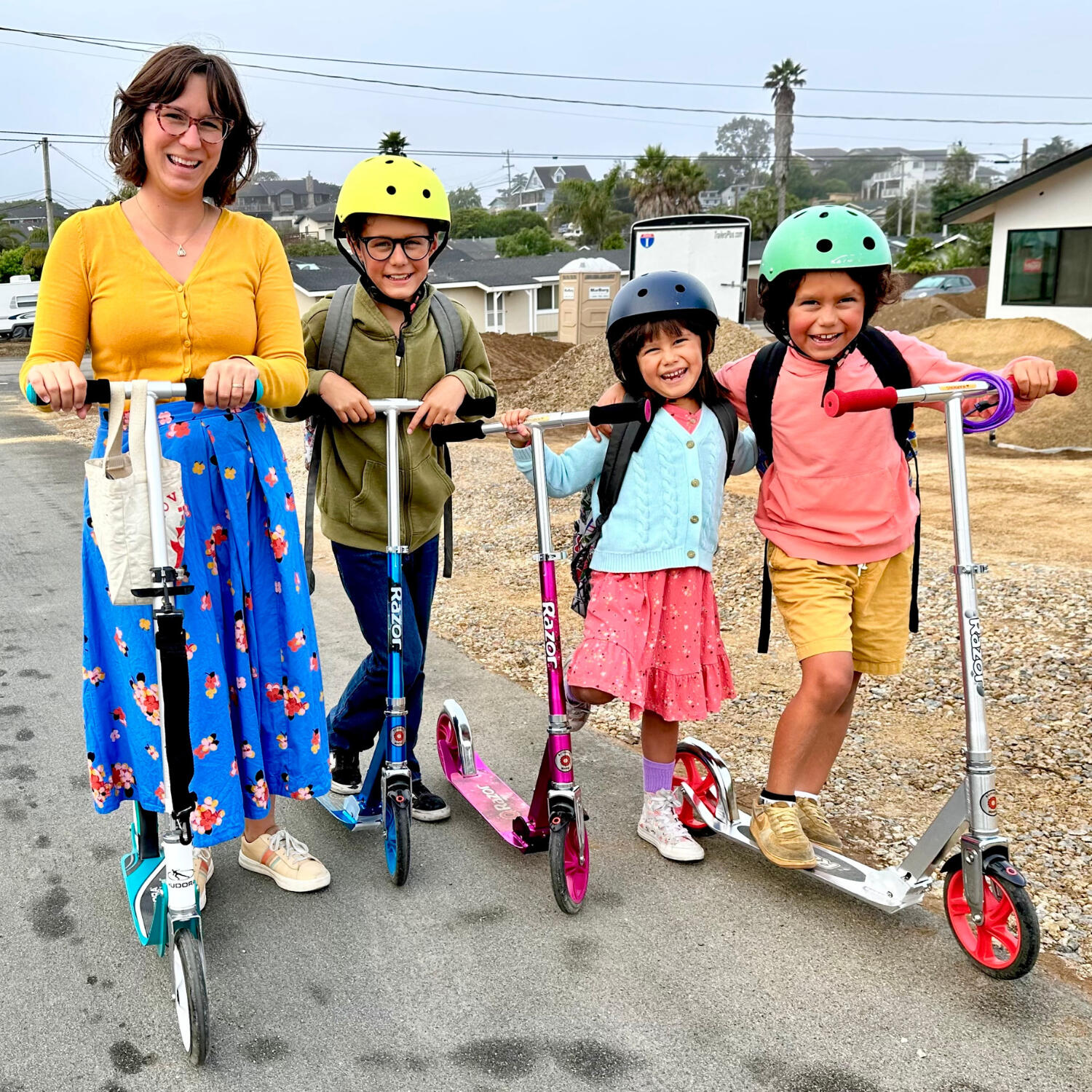 Marisa Gomez and her three children dressed in colorful clothing, all riding scooters