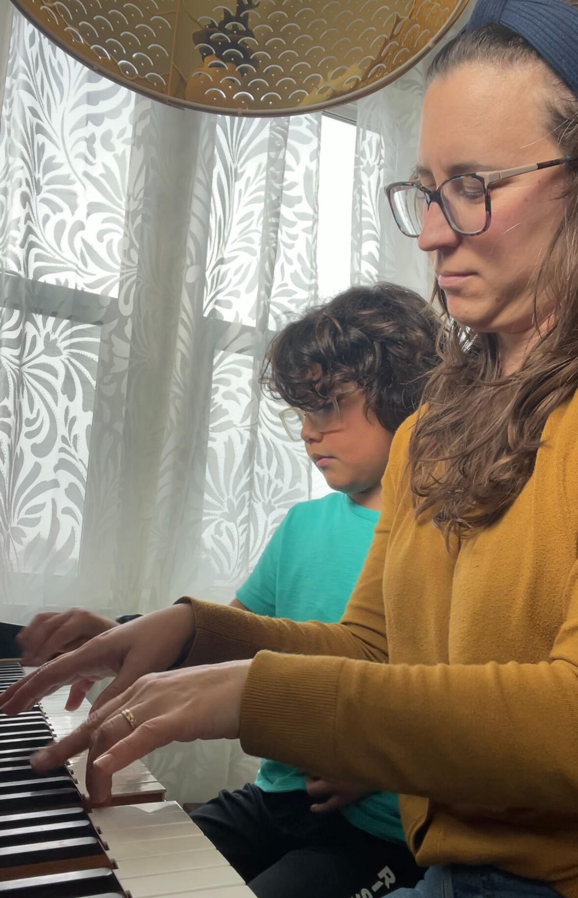 Marisa Gomez and her son playing a duet on the piano